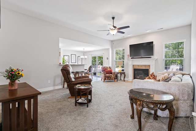 carpeted living room with a ceiling fan, a fireplace, baseboards, and a chandelier