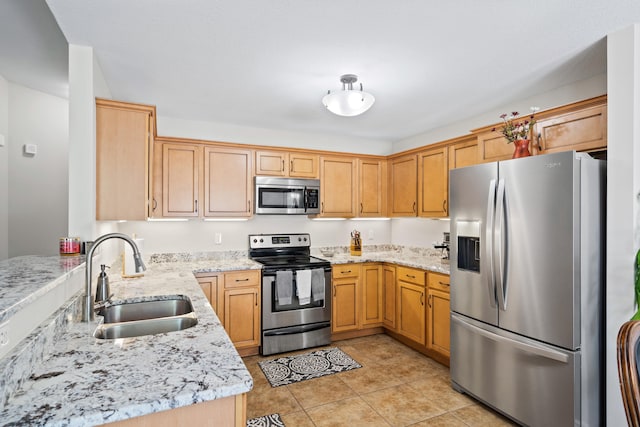 kitchen featuring stainless steel appliances, a sink, light stone counters, and light tile patterned floors