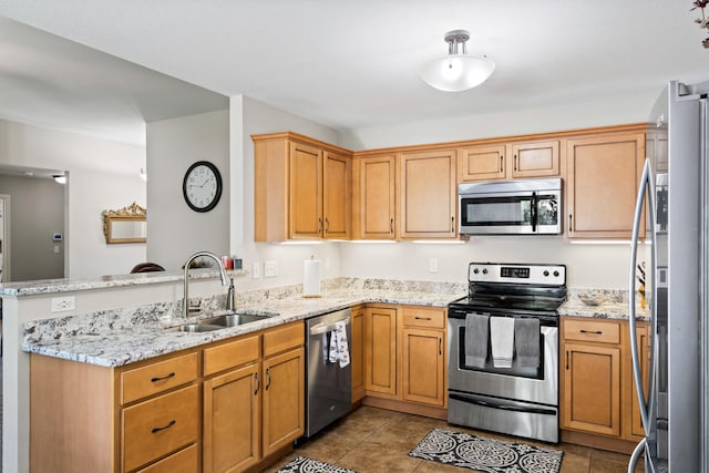kitchen with stainless steel appliances, a sink, a peninsula, light stone countertops, and tile patterned flooring