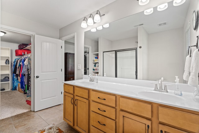 bathroom with double vanity, a stall shower, a spacious closet, and tile patterned floors