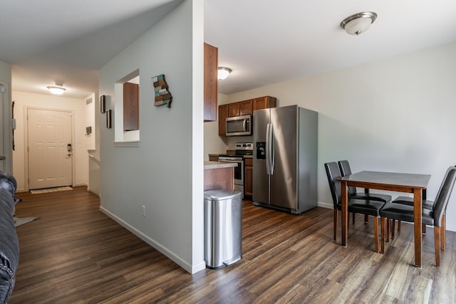 kitchen featuring appliances with stainless steel finishes, dark wood-type flooring, baseboards, and light countertops