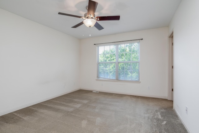 carpeted spare room featuring a ceiling fan and baseboards