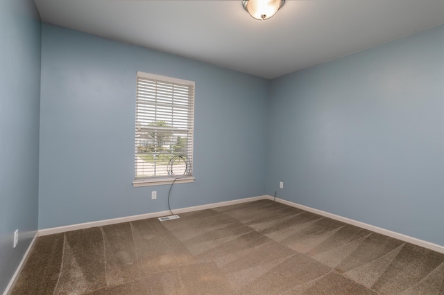 empty room with dark carpet and baseboards