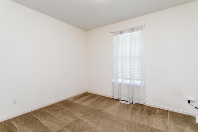 carpeted spare room with plenty of natural light and baseboards