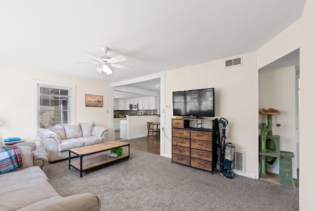 living area with carpet, visible vents, baseboards, and ceiling fan