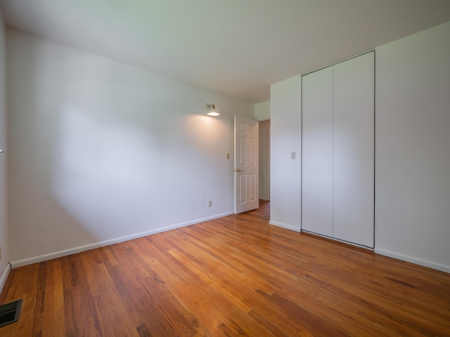 unfurnished bedroom featuring light wood-style floors, baseboards, and a closet