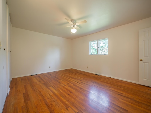 empty room featuring ceiling fan, wood finished floors, and baseboards