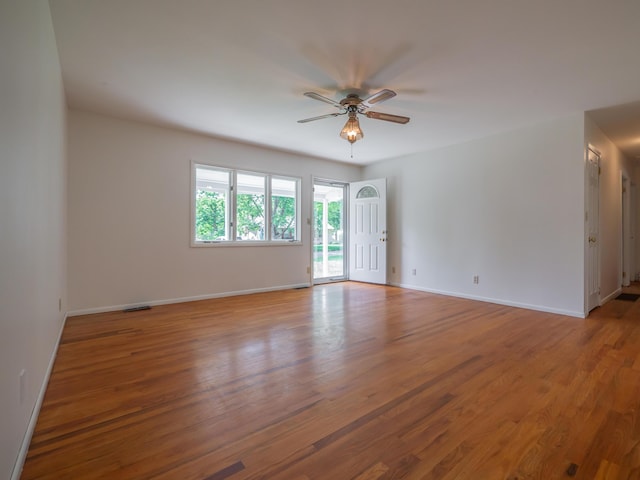 unfurnished room with ceiling fan, wood finished floors, and baseboards