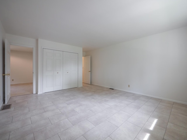 unfurnished bedroom with a closet, baseboards, and light tile patterned flooring