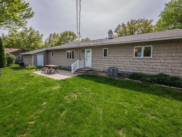 rear view of property with a patio area, cooling unit, a yard, and a chimney