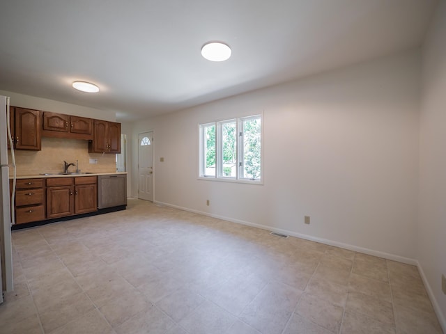 kitchen featuring dishwashing machine, light countertops, a sink, and baseboards