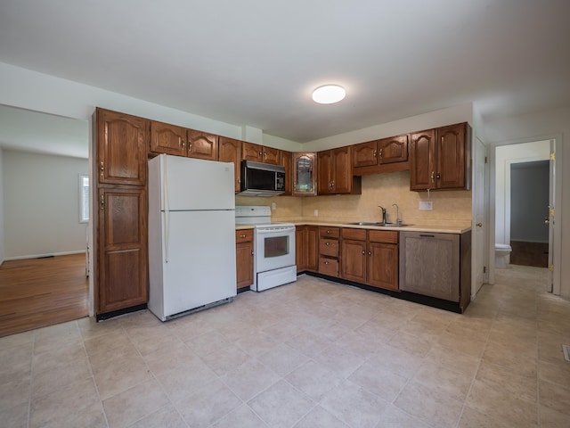 kitchen featuring white appliances, a sink, light countertops, tasteful backsplash, and baseboards