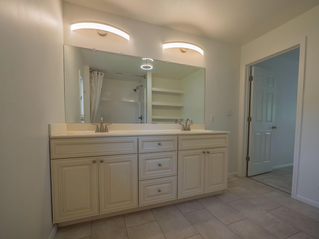 full bath featuring double vanity, a shower with shower curtain, baseboards, and tile patterned floors