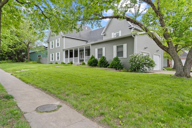view of front of property with a front yard, a garage, a sunroom, and roof with shingles