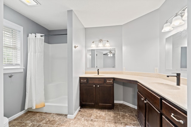 bathroom with baseboards, curtained shower, double vanity, and a ceiling fan