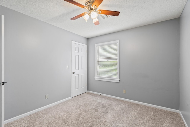 carpeted empty room with a ceiling fan, baseboards, and a textured ceiling