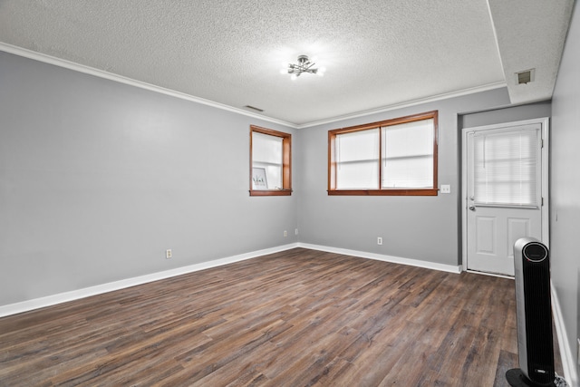 empty room featuring a textured ceiling, dark wood finished floors, crown molding, and baseboards