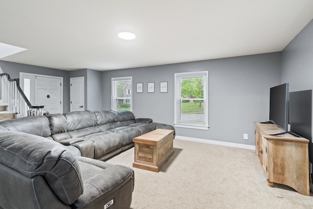 living room featuring baseboards, plenty of natural light, light carpet, and stairway
