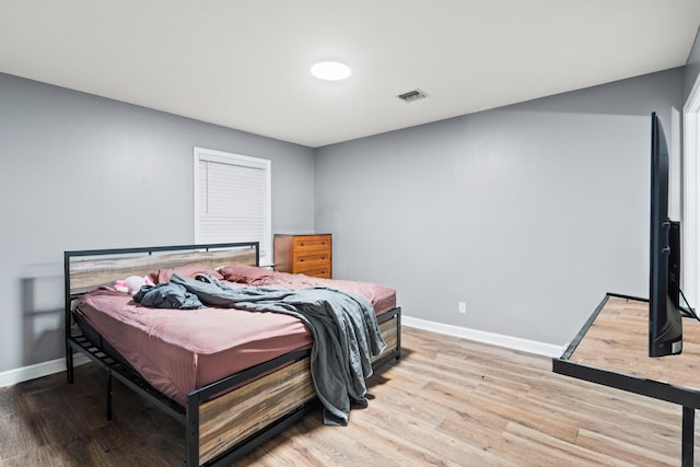 bedroom featuring light wood finished floors and baseboards