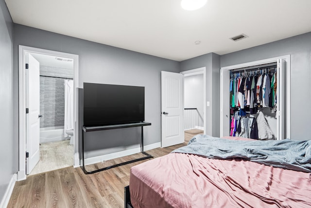 bedroom featuring wood finished floors, a closet, baseboards, and connected bathroom