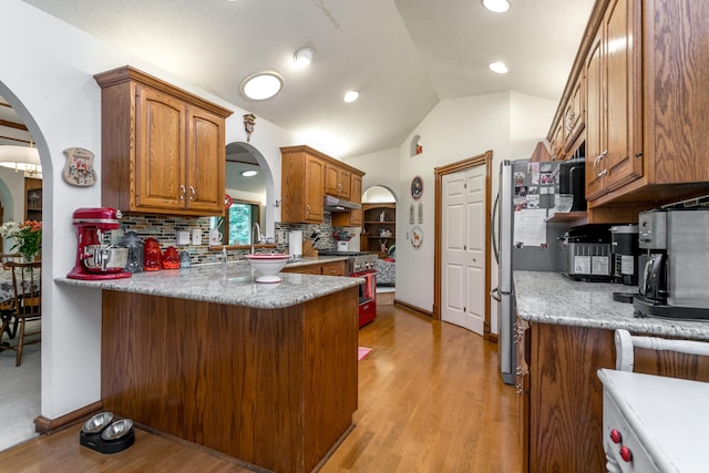 2105 Oak Point Ct, Columbia, MO 65203 - kitchen with stainless steel appliances, arched walkways, under cabinet range hood, light wood-type flooring, and vaulted ceiling