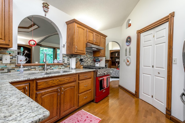 2105 Oak Point Ct, Columbia, MO 65203 - kitchen featuring stainless steel range, under cabinet range hood, lofted ceiling, a sink, and arched walkways