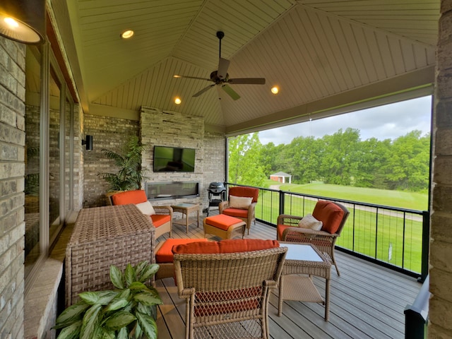 wooden terrace with an outdoor living space with a fireplace and a ceiling fan