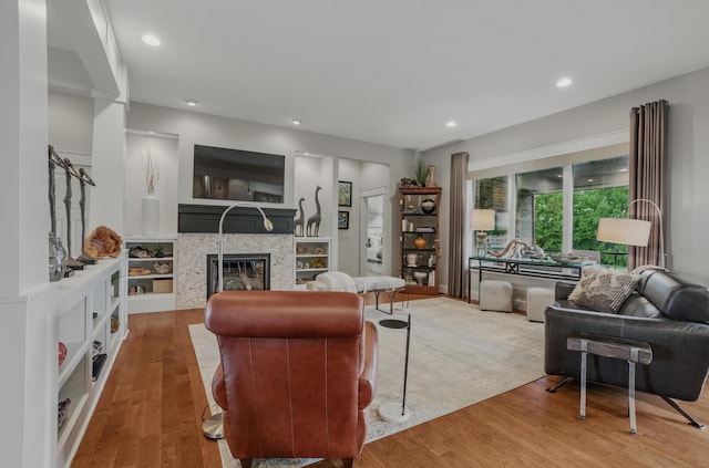 living area featuring a glass covered fireplace, wood finished floors, and recessed lighting