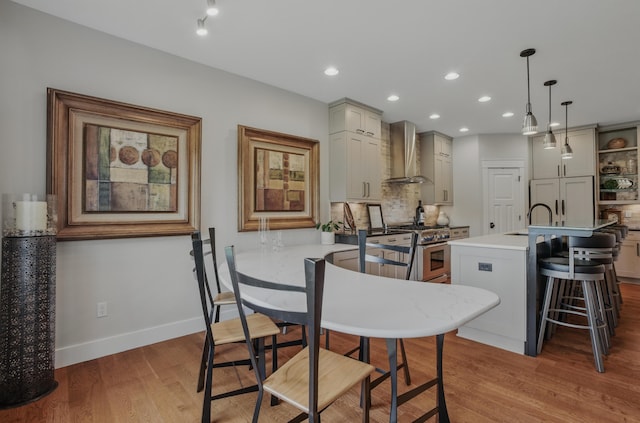 kitchen with wall chimney exhaust hood, stainless steel stove, a sink, tasteful backsplash, and light countertops