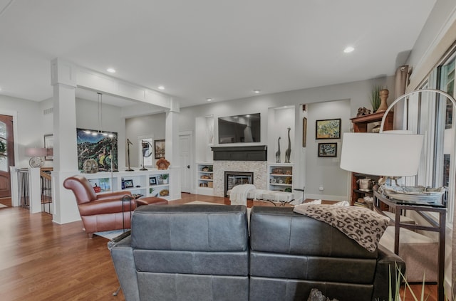 living room featuring wood finished floors, a glass covered fireplace, recessed lighting, and baseboards