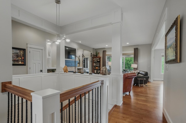 hall with an upstairs landing, wood finished floors, and recessed lighting