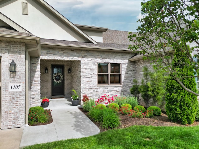 property entrance with stucco siding, stone siding, and brick siding