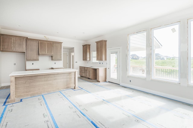 4725 Stayton Ferry Cir, Columbia, MO 65201 - kitchen featuring plenty of natural light, a kitchen island, baseboards, and brown cabinets