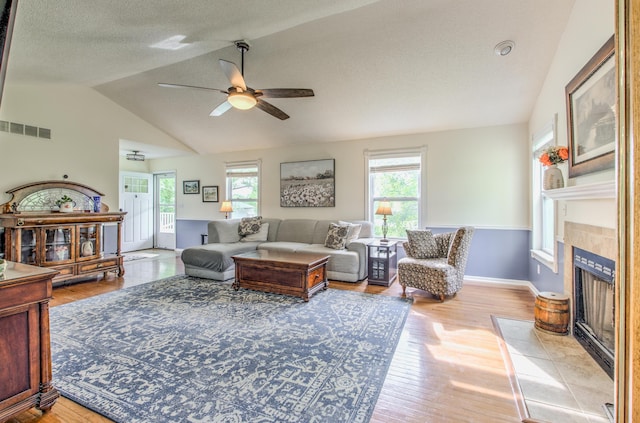 living area featuring ceiling fan, a fireplace, wood finished floors, lofted ceiling, and baseboards