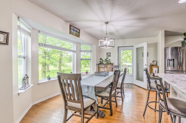 dining area featuring plenty of natural light, light wood-style floors, a textured ceiling, and baseboards