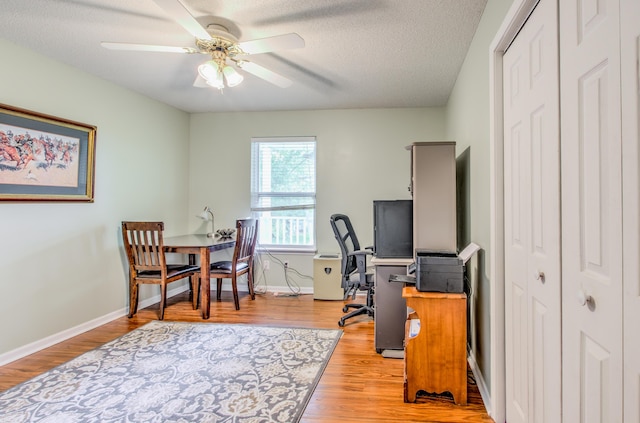 office space with ceiling fan, light wood-style floors, a textured ceiling, and baseboards