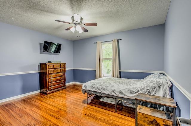 bedroom with wood finished floors, baseboards, a textured ceiling, and ceiling fan