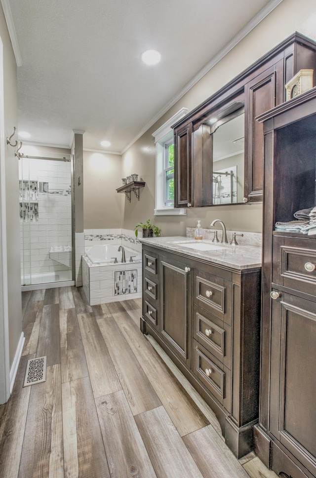bathroom with a garden tub, vanity, wood finished floors, crown molding, and a shower stall