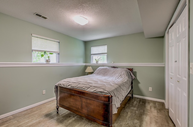 bedroom featuring wood finished floors, baseboards, and a textured ceiling