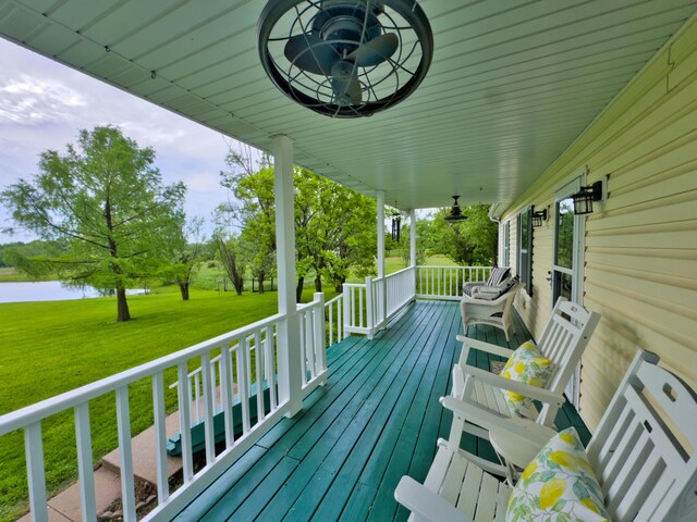 deck with covered porch, a lawn, and a water view