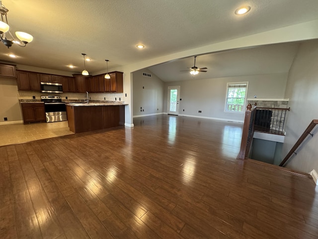 unfurnished living room with baseboards, ceiling fan, wood finished floors, a sink, and a textured ceiling