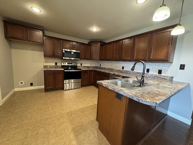kitchen with stainless steel appliances, a sink, tasteful backsplash, a peninsula, and baseboards