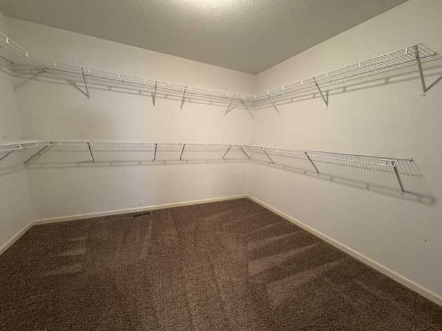 walk in closet with dark carpet