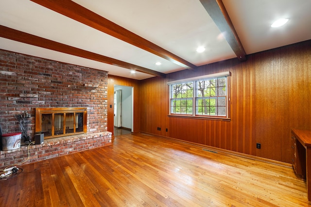 10155 E Union Church Rd, Centralia, MO 65240 - unfurnished living room featuring hardwood / wood-style flooring, beamed ceiling, a fireplace, and wooden walls
