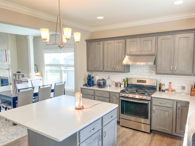 kitchen with gas range, under cabinet range hood, gray cabinetry, light wood-type flooring, and light countertops