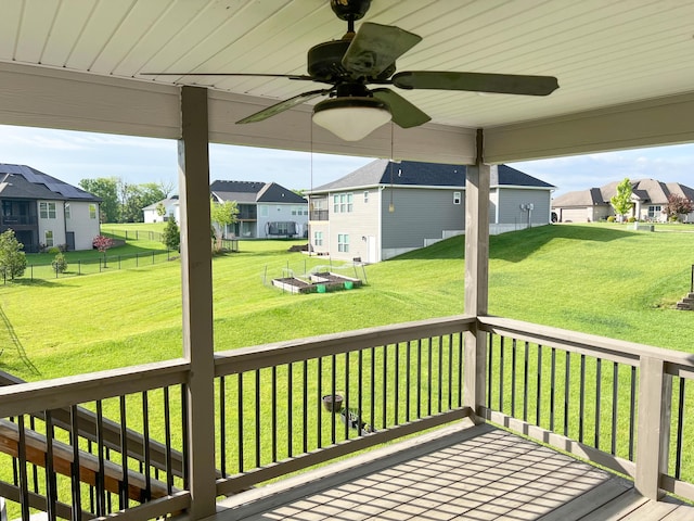 wooden terrace featuring a residential view, ceiling fan, and a yard