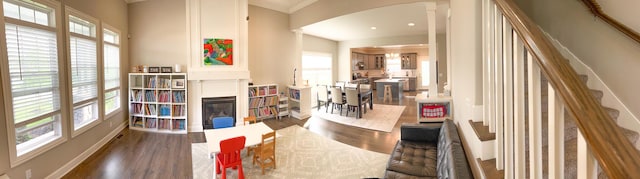 living area featuring wood finished floors, healthy amount of natural light, and arched walkways