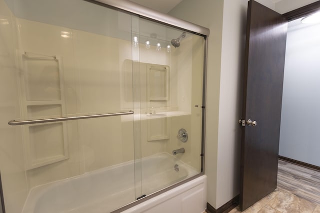 full bath featuring baseboards and shower / bath combination with glass door