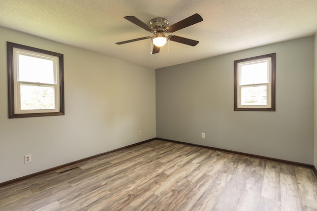 unfurnished room featuring wood finished floors, ceiling fan, baseboards, and a textured ceiling