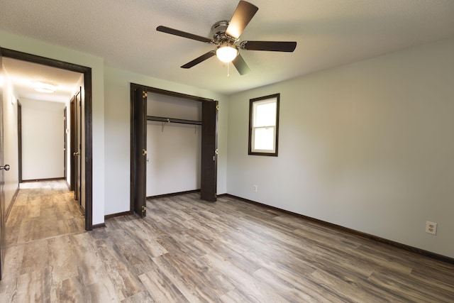 unfurnished bedroom featuring wood finished floors, baseboards, and a closet